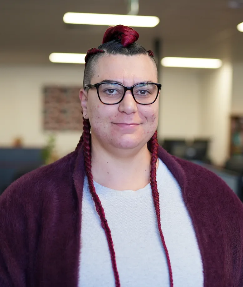 Sara, smiling, wearing glasses and a burgundy cardigan